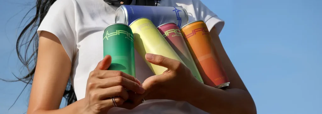 A person holding colourful Kyro Hydration drink cans against a blue sky
