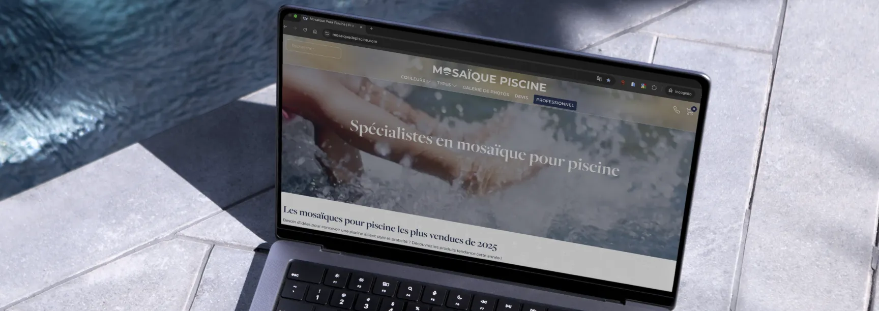 Laptop displaying the Mosaïque Piscine website, resting on stone tiles beside a pool